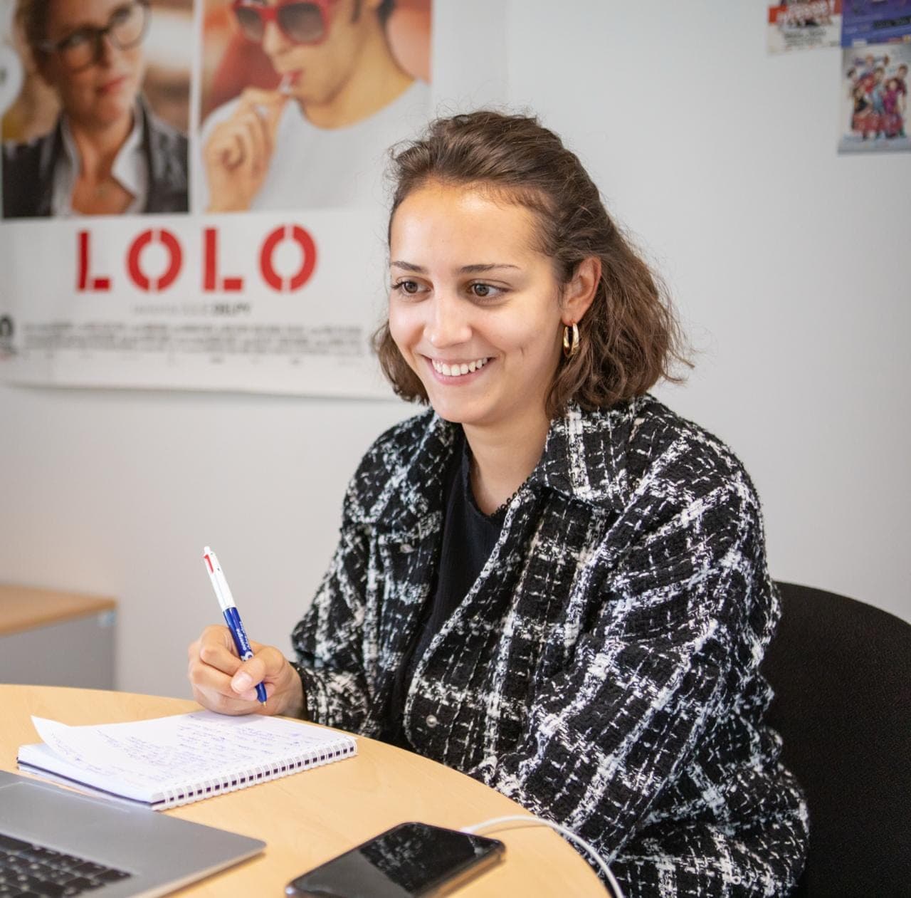 Mélanie Galichon souriante, carnet et stylo en main, à son bureau.